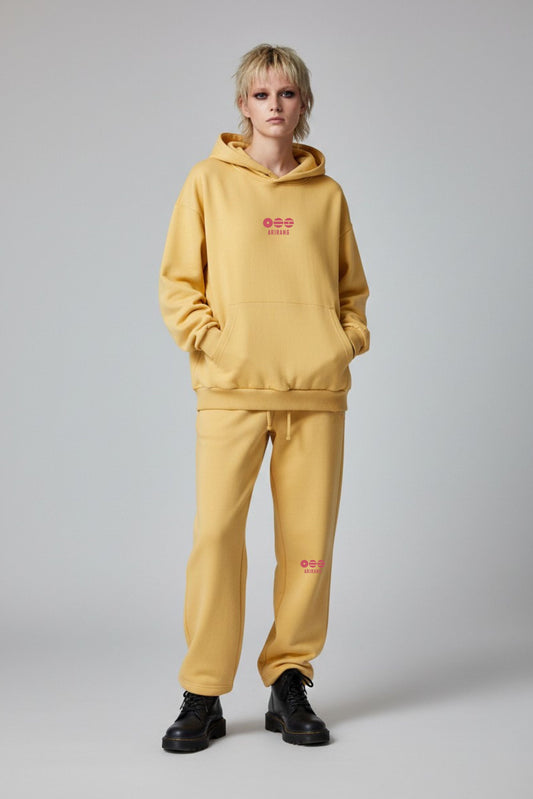 Person wearing a mustard yellow hoodie and pants with red text on a gray background