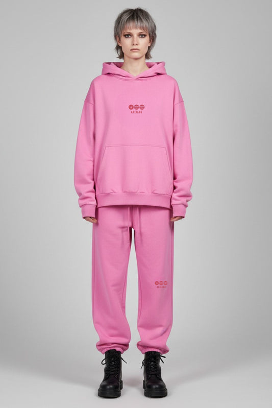 Person wearing a pink hoodie and pants set on a gray background
