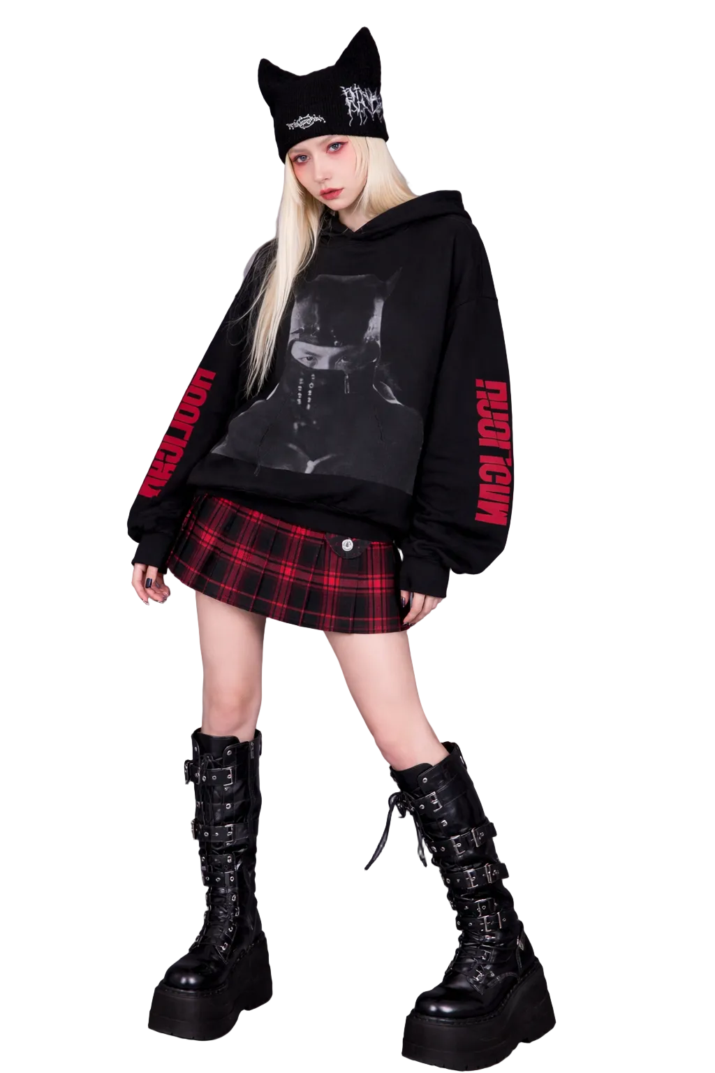 Person wearing a black hoodie with red text, plaid skirt, and black boots on a gray background