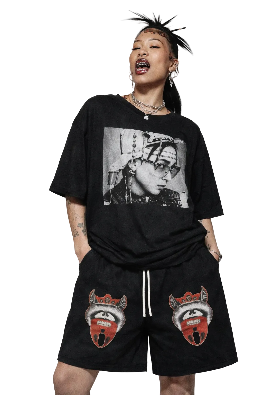 Person wearing a black t-shirt with a graphic design and black shorts with red and white designs on a plain background