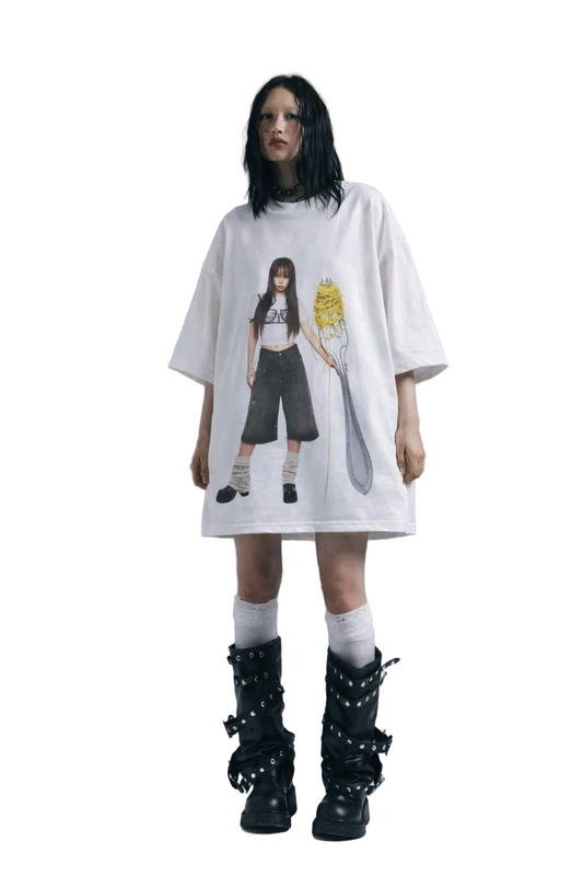 Person wearing a white oversized t-shirt with a graphic design on a plain background