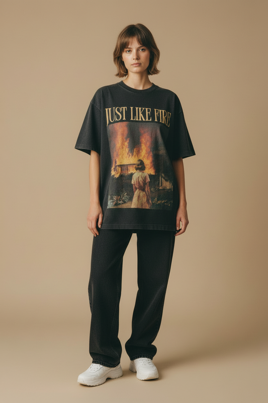 T-shirt with a graphic design of a person looking at a burning building and the text 'Just Like Fire' on a white background.