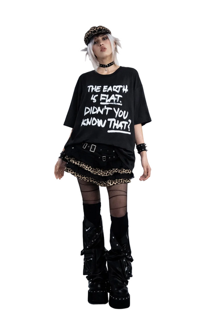 Person wearing a black t-shirt with text, skirt, and boots on a gray background